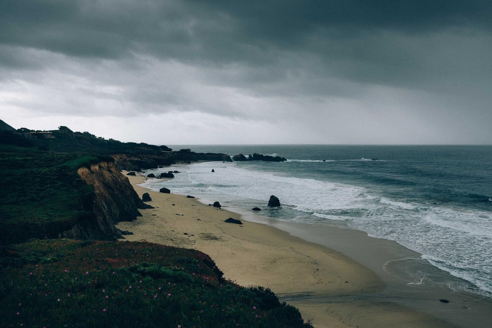A beach and dunes below a stormy sky