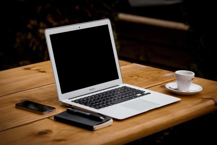 A laptop and phone on a wooden desk