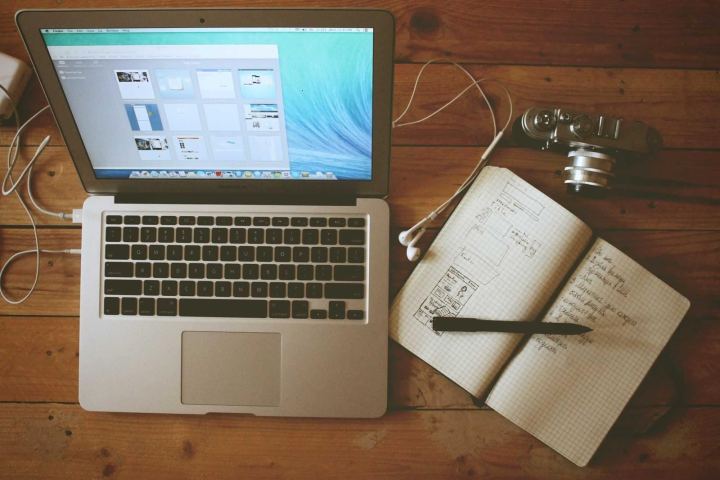 A laptop and an open notebook on a desk