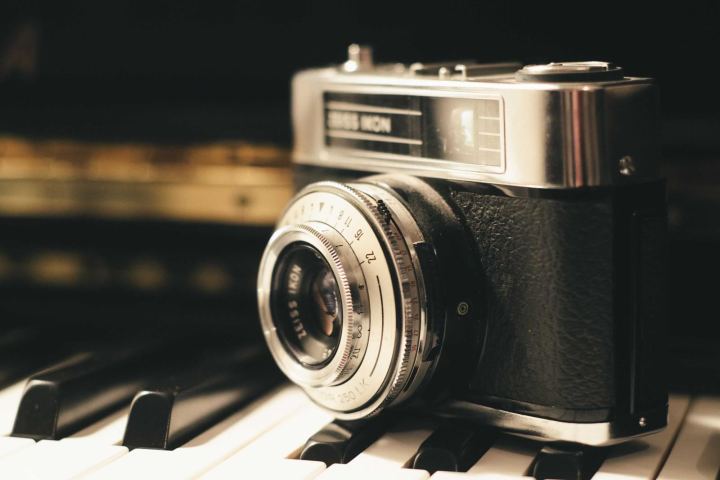 A vintage film camera resting on piano keys