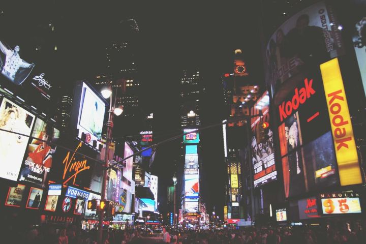 Neon billboards over a busy street at night