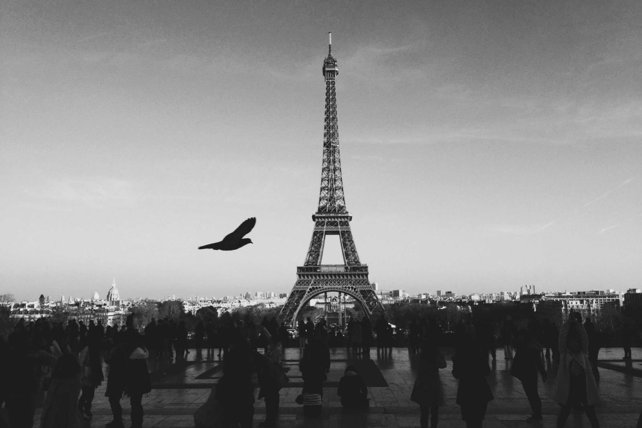 The Eiffel Tower above a crowd, in black and white